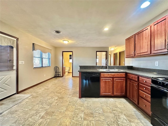 kitchen featuring baseboards, a peninsula, a sink, black appliances, and dark countertops