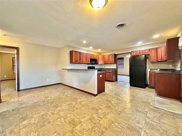 kitchen featuring dark countertops, visible vents, baseboards, a peninsula, and black appliances