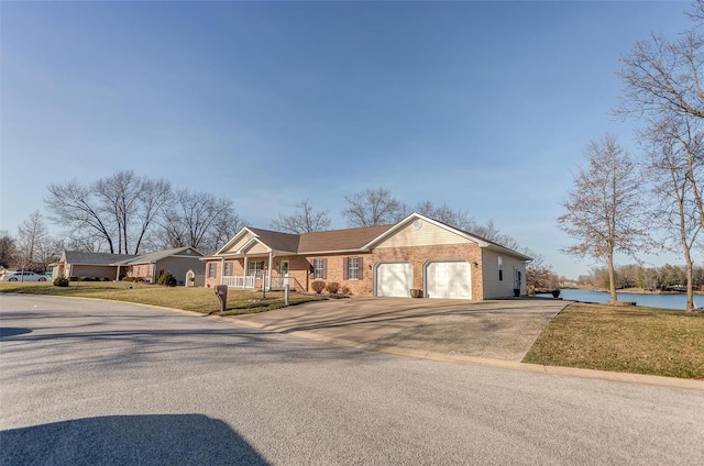 ranch-style home featuring a water view, driveway, a front lawn, a garage, and brick siding