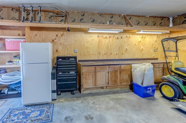 basement with a workshop area and freestanding refrigerator