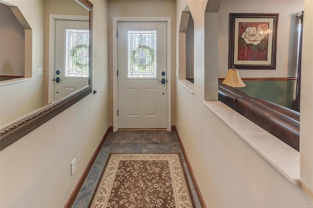 doorway to outside with baseboards and stone finish flooring