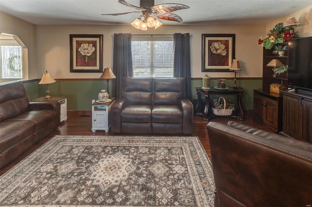 living room with wood finished floors, arched walkways, and ceiling fan