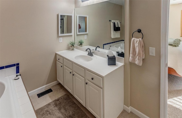 bathroom with vanity, baseboards, visible vents, tile patterned flooring, and a bathtub