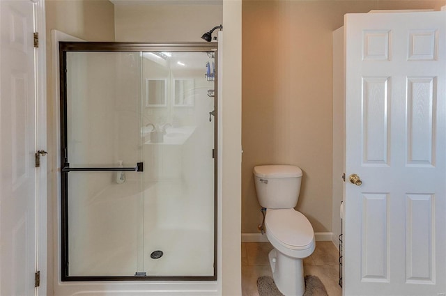 bathroom with tile patterned floors, toilet, baseboards, and a stall shower