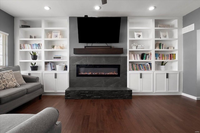 living area featuring recessed lighting, built in features, dark wood-style flooring, and a tile fireplace