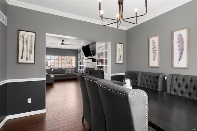 dining space featuring built in features, baseboards, a tile fireplace, ornamental molding, and dark wood-type flooring