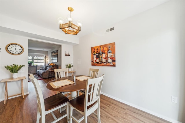 dining room with a chandelier, visible vents, baseboards, and light wood-style floors