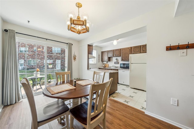 dining area featuring baseboards, light wood-style floors, and a chandelier