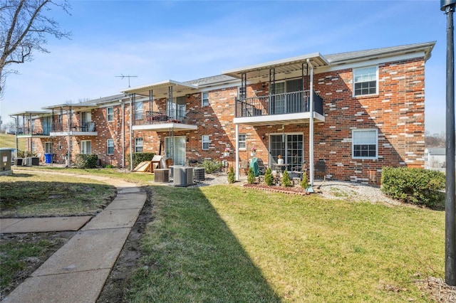 rear view of property with a yard, central AC unit, and brick siding