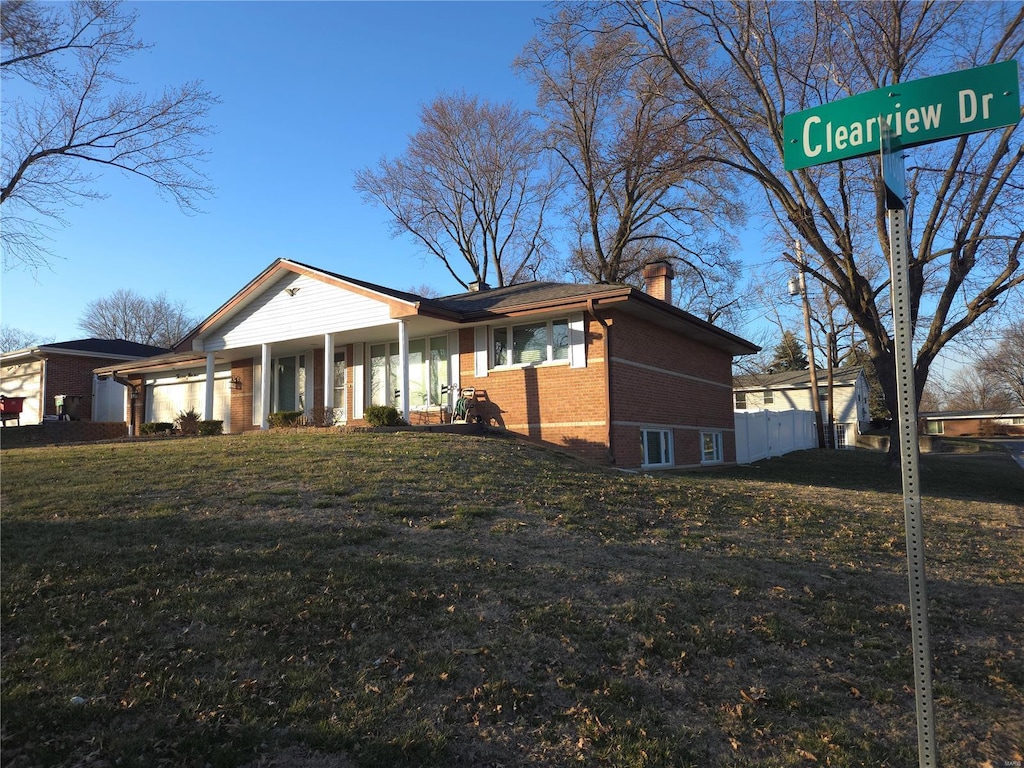 view of front of house with brick siding, a chimney, a front lawn, and fence