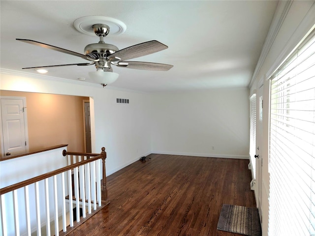 unfurnished room featuring visible vents, dark wood-type flooring, baseboards, and ornamental molding