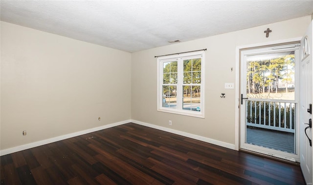 spare room with visible vents, baseboards, a textured ceiling, and dark wood-style flooring