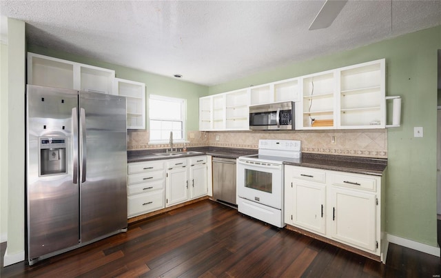 kitchen with dark countertops, a sink, stainless steel appliances, and open shelves