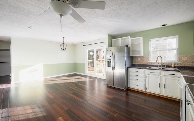 kitchen with dark countertops, dark wood finished floors, stainless steel fridge, white electric stove, and a sink