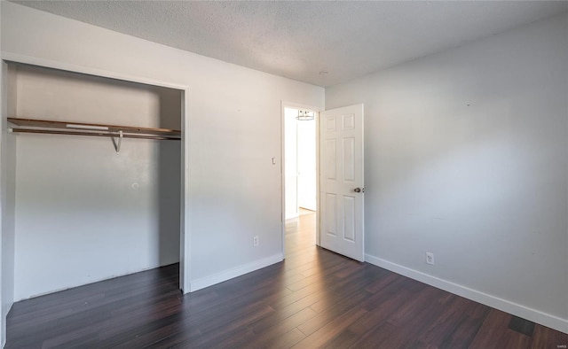 unfurnished bedroom featuring dark wood finished floors, baseboards, a textured ceiling, and a closet