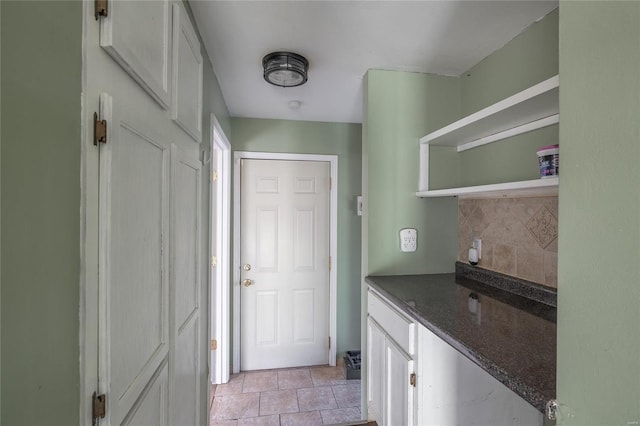 kitchen featuring open shelves, decorative backsplash, white cabinets, and dark stone counters