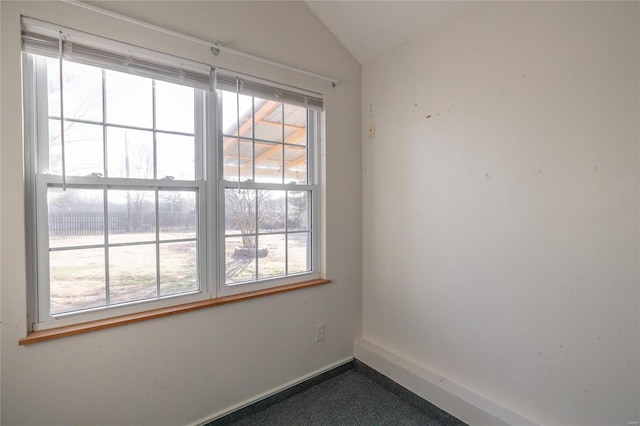 spare room with baseboards and lofted ceiling