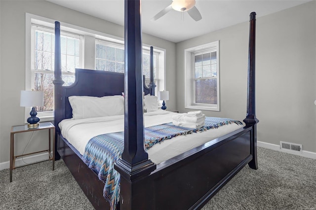 carpeted bedroom with visible vents, multiple windows, a ceiling fan, and baseboards