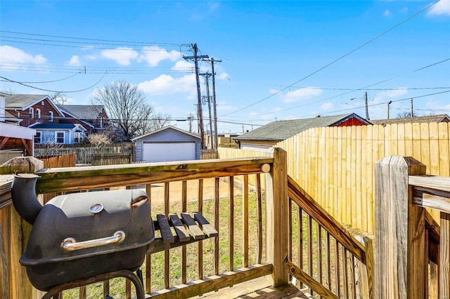 wooden deck with grilling area, a detached garage, an outdoor structure, and fence