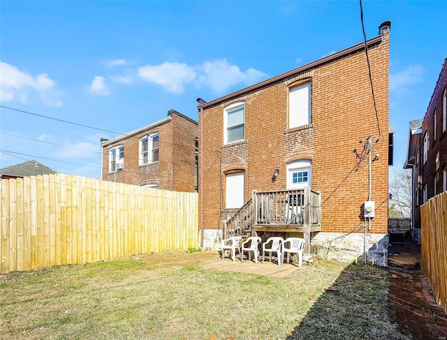 rear view of property featuring a yard, a fenced backyard, and brick siding