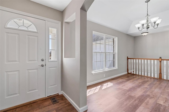 foyer featuring vaulted ceiling, a notable chandelier, wood finished floors, and baseboards