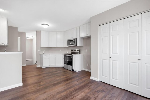 kitchen featuring stainless steel appliances, baseboards, dark wood finished floors, and white cabinetry