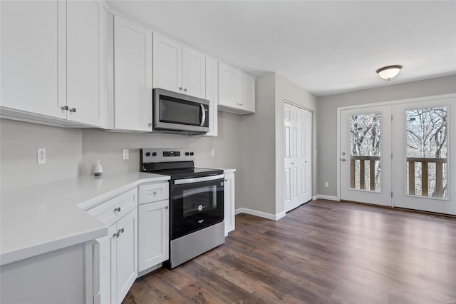 kitchen with appliances with stainless steel finishes, white cabinetry, light countertops, and dark wood-style flooring