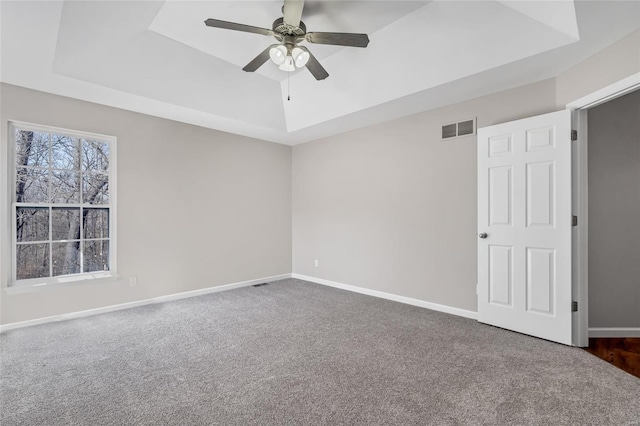 unfurnished room featuring carpet, a raised ceiling, baseboards, and visible vents