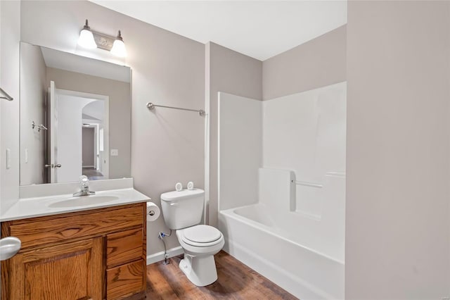 bathroom with vanity, wood finished floors, baseboards, bathing tub / shower combination, and toilet