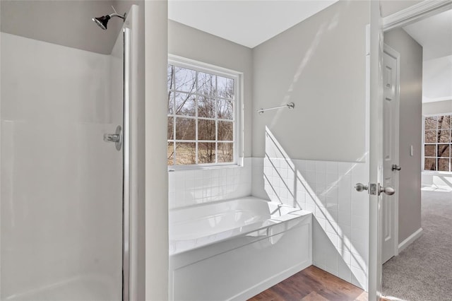 bathroom with a bath, a stall shower, and wood finished floors