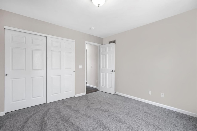 unfurnished bedroom with dark colored carpet, visible vents, baseboards, and a closet