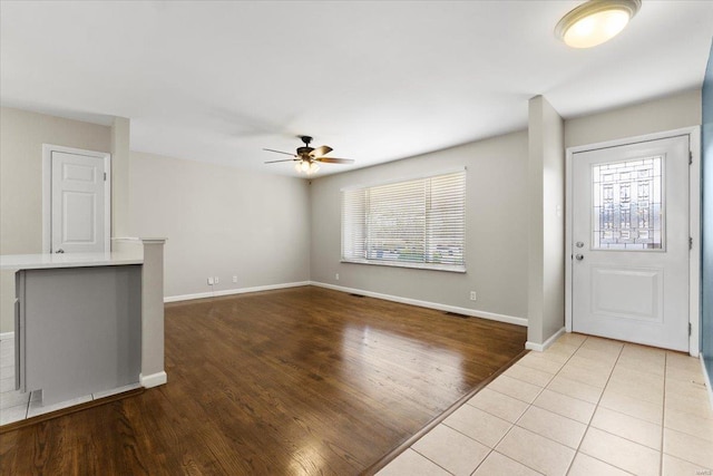 foyer entrance with baseboards, ceiling fan, and light wood finished floors