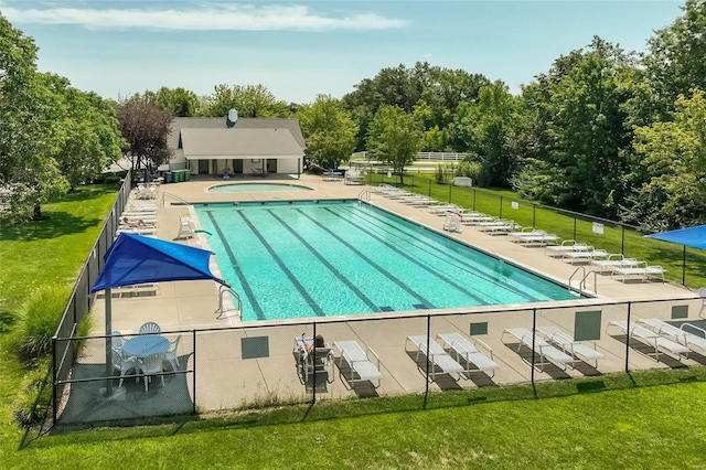 community pool with a yard, a patio, and fence