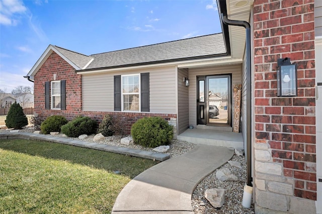 entrance to property with brick siding and a shingled roof