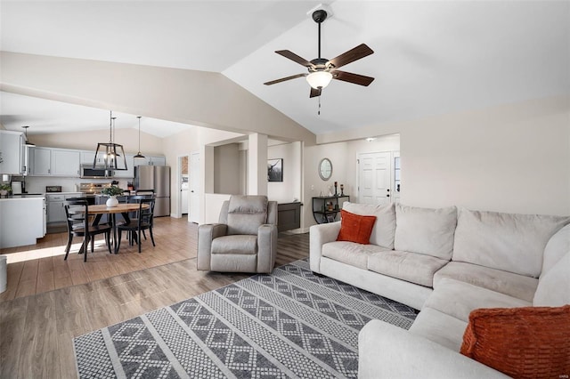 living room with vaulted ceiling, a ceiling fan, and light wood-style floors