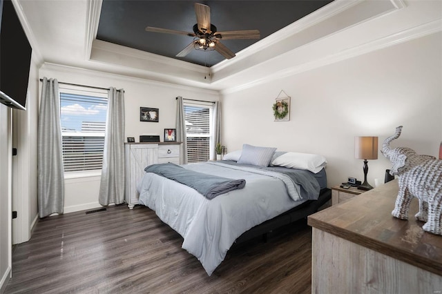 bedroom with dark wood-style floors, visible vents, a raised ceiling, and ornamental molding