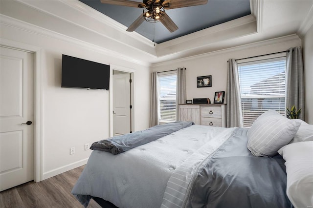 bedroom with a tray ceiling, baseboards, dark wood-type flooring, and crown molding