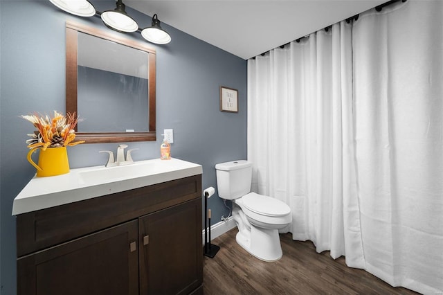 bathroom with toilet, vanity, baseboards, and wood finished floors