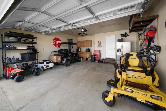 garage with a garage door opener and stainless steel fridge with ice dispenser