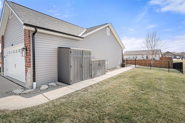 rear view of property with fence, a yard, an attached garage, a shingled roof, and brick siding