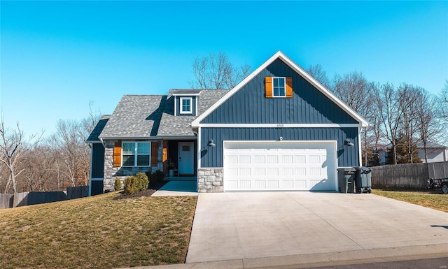 view of front of home featuring fence, roof with shingles, a front yard, stone siding, and an attached garage