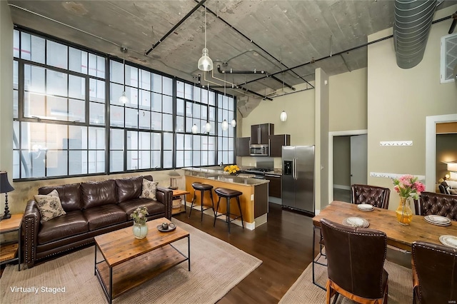 living room with dark wood-type flooring and a towering ceiling