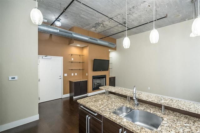 kitchen featuring a sink, visible vents, pendant lighting, and dark brown cabinets