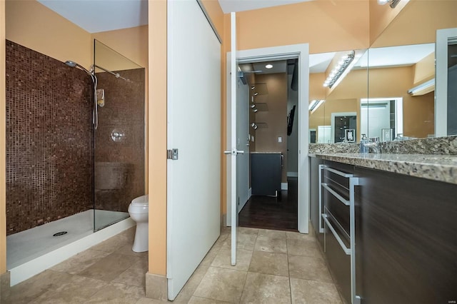 full bathroom with a tile shower, tile patterned flooring, toilet, and vanity