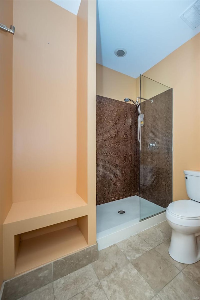 bathroom with visible vents, toilet, and a tile shower