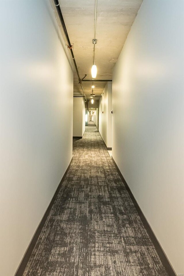 hallway featuring carpet flooring and baseboards