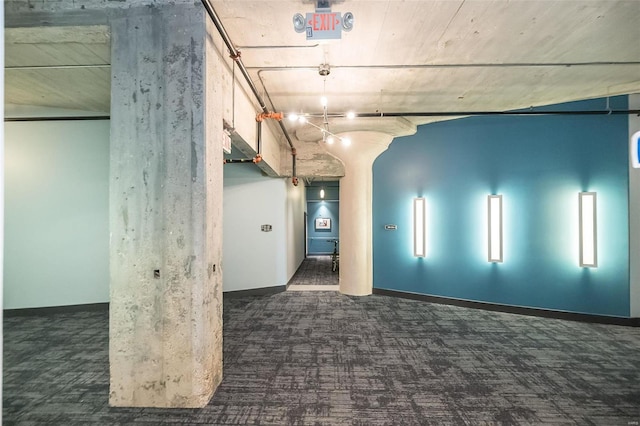 carpeted empty room with baseboards and arched walkways