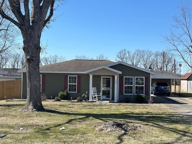 view of front of house with fence, roof with shingles, driveway, a front lawn, and a carport