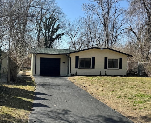 ranch-style home with brick siding, an attached garage, fence, a front yard, and driveway