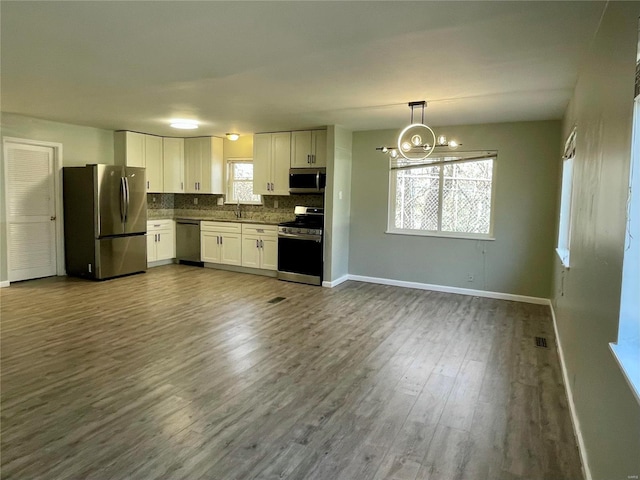 kitchen featuring dark wood finished floors, white cabinetry, appliances with stainless steel finishes, decorative backsplash, and baseboards